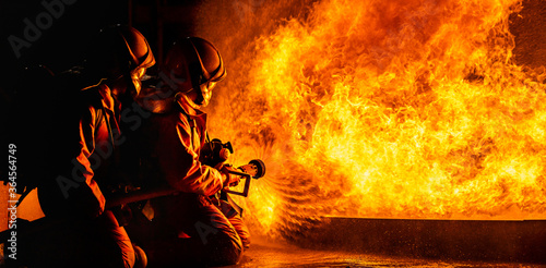 Billede på lærred Firefighters use twirl water fog spraying down fire flame.