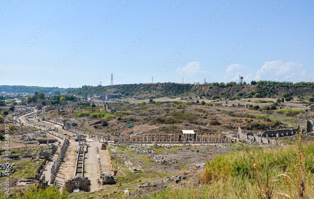 Remains of ancient greek columns and buildings against a clear blue sky of ancient ancient Anatolian city of Perge located near the Antalya city in Turkey