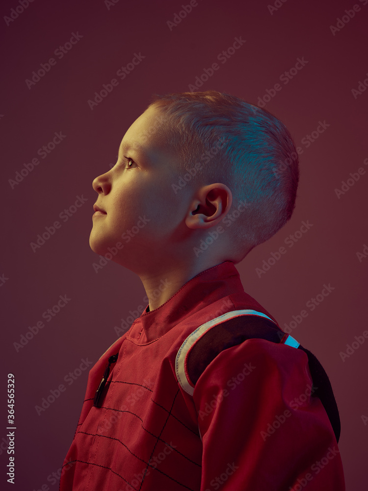 Portrait of boy kid racer in racing suit, standing in neon light. Kart racing school poster. Competition announcement