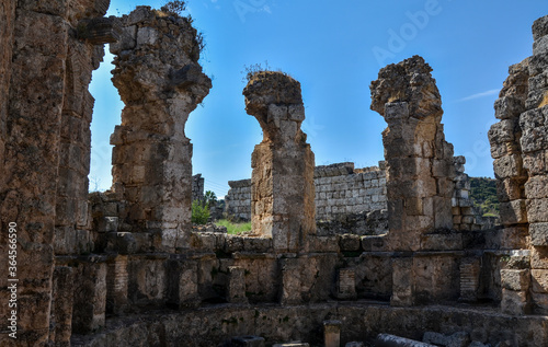Remains of ancient greek columns and buildings against a clear blue sky of ancient ancient Anatolian city of Perge located near the Antalya city in Turkey