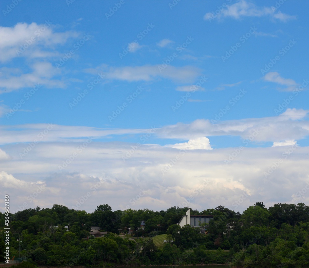 The white clouds in the sky over the town landscape.