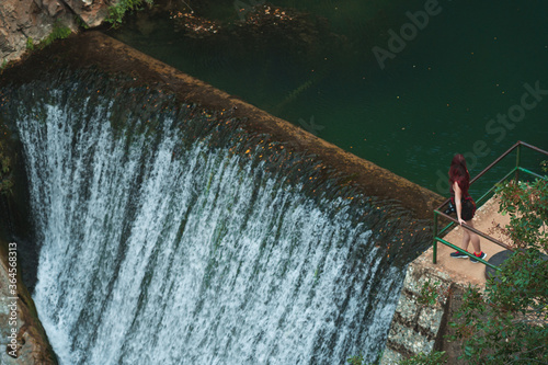 Aerial shot of red head nearby a waterfall in summer