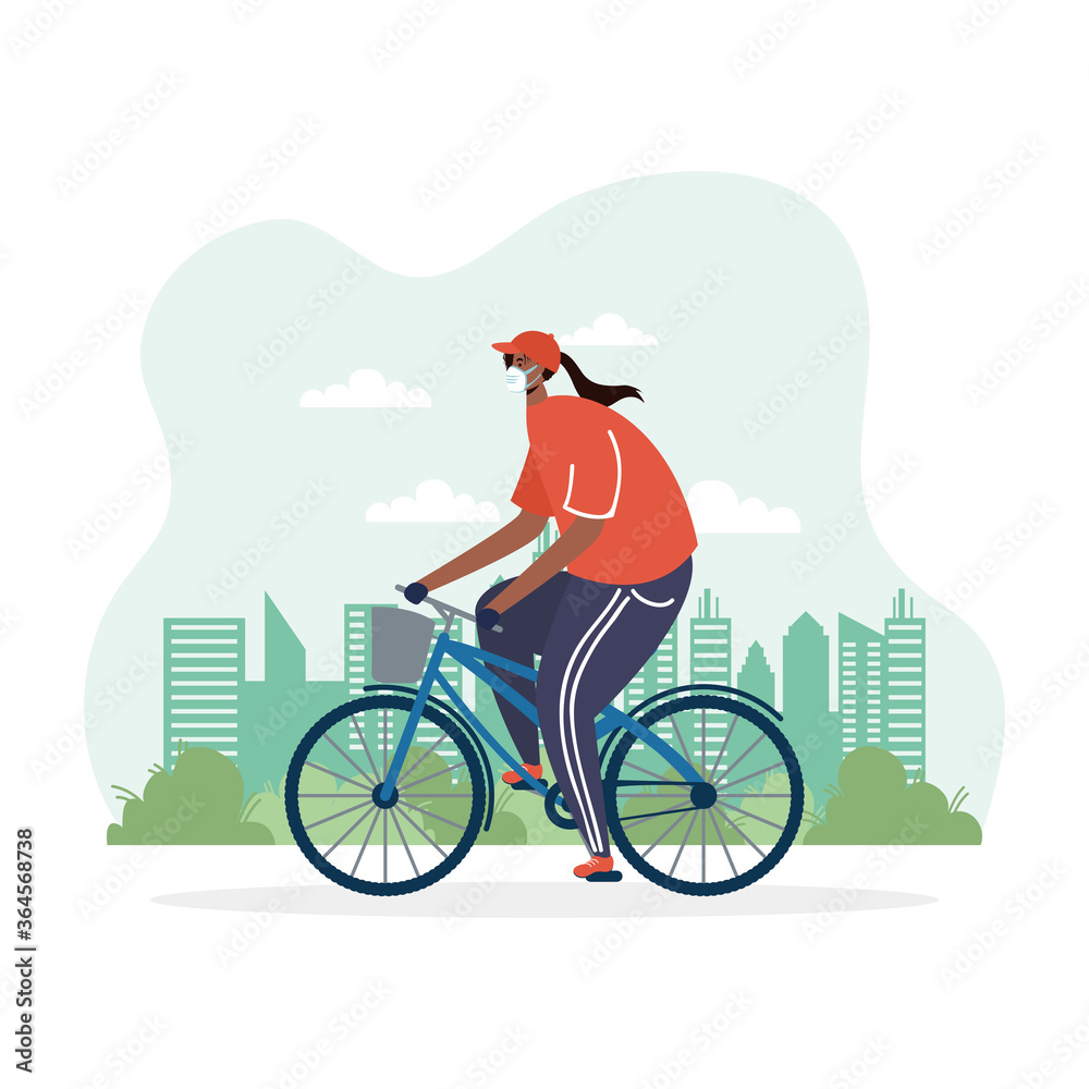 Fototapeta premium young afro woman riding bicycle wearing medical mask