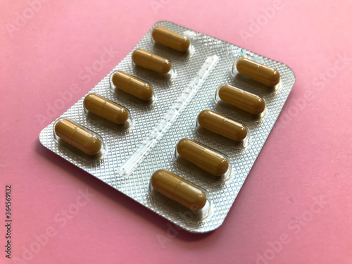 bright brown oblong tablets to strengthen the immune system. preparations on herbs and extracts. Prescribed medicines for the human body. pills on a pink background photo