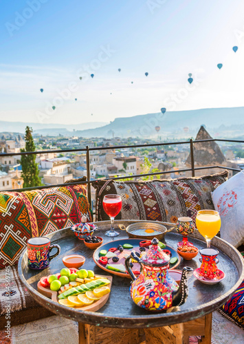 Traditional turkish breakfast with Cappadocia view and flying balloons on the background. Goreme, Turkey..