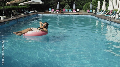 Woman is floating with an inflatable donut circle in the swomming pool © stanis88