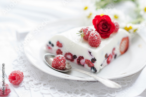 Dessert of yogurt , berries and gelatin, decorated with raw raspberries and natural red rose in white background, fresh, healthy food 