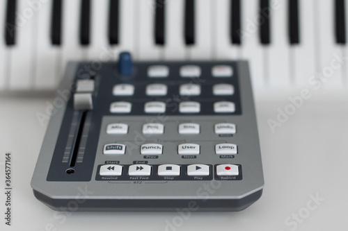 Canvas Print Closeup of an daw (digital audio workstation) controller on a table with piano keys on the background