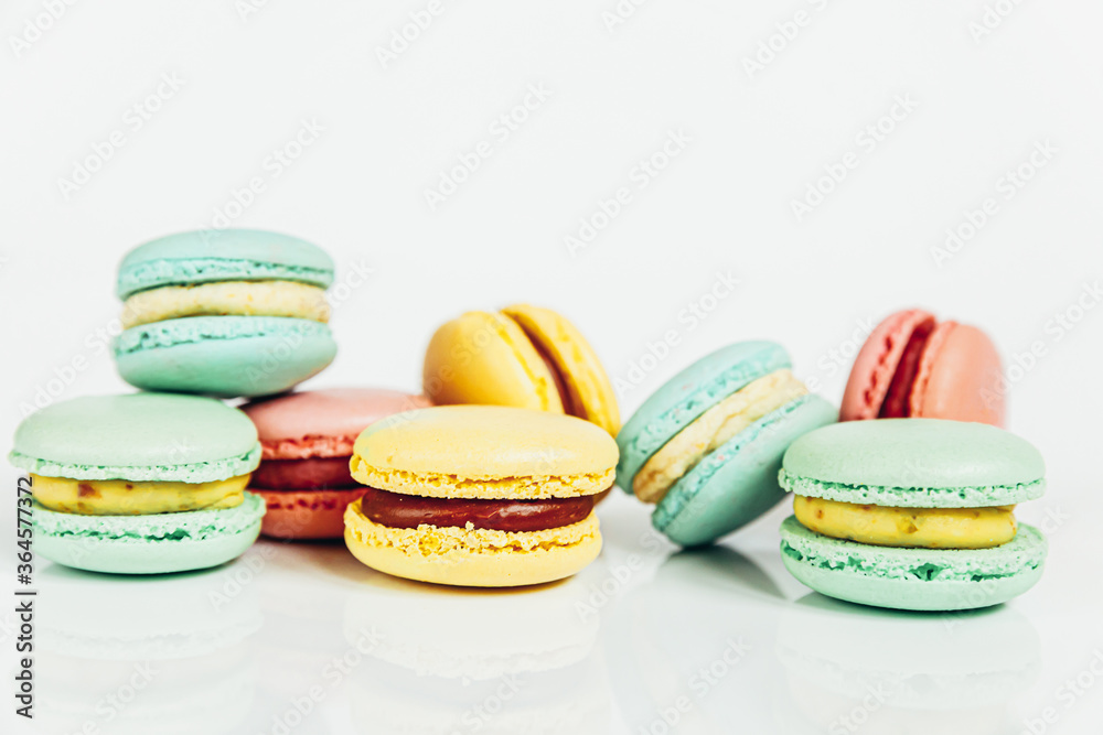 Obraz premium Sweet almond colorful pastel pink blue yellow green macaron or macaroon dessert cake isolated on white background. French sweet cookie. Minimal food bakery concept Copy space
