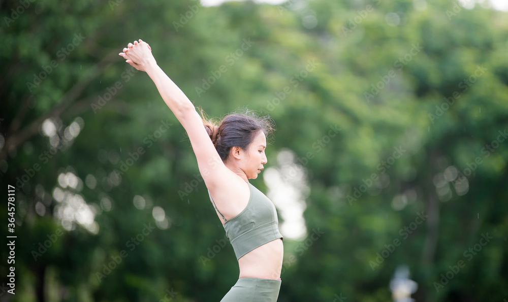 Asian model poses yoga in a park on a natural green background, health care concept, beautiful body structure, fit body