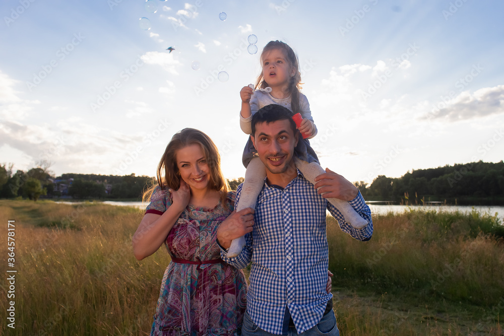 Happy young family walks in nature, at sunset