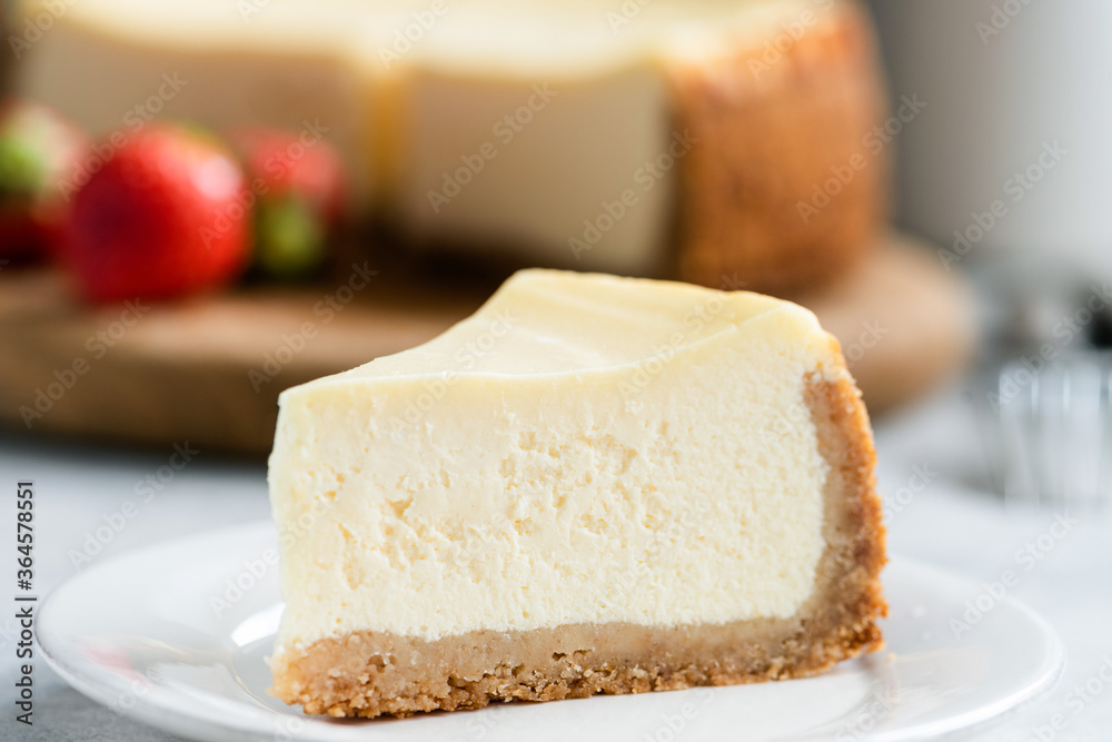 Slice of classic new york cheesecake on white plate, closeup view