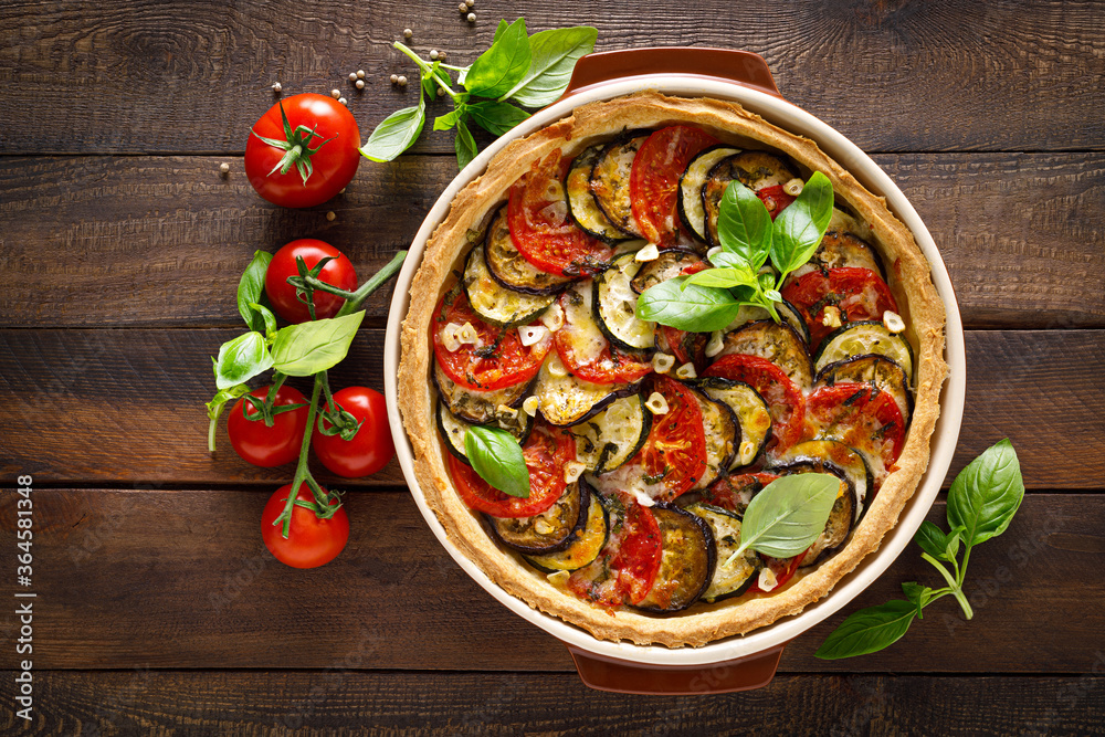 Tart with vegetables. Homemade savory tart with eggplant, zucchini, tomatoes, garlic, mozzarella cheese and fresh basil. Mediterranean cuisine. View from above Tart with vegetables. Homemade savory tart with eggplant, zucchini, tomatoes, garlic, mozzarella cheese and fresh basil. Mediterranean cuisine. View from above