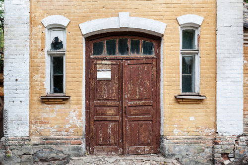 Closeup of old building with wooden door and brick wall.