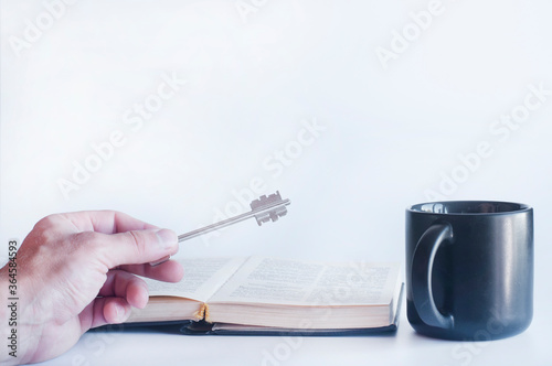 Open book Bible and cup. Iron key. The concept of the path to knowledge