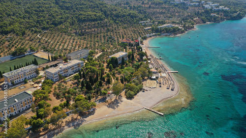 Aerial drone photo of organised with sun beds emerald beach of Kaikia in Ligoneri area near old town of Spetses island, Saronic gulf, Greece