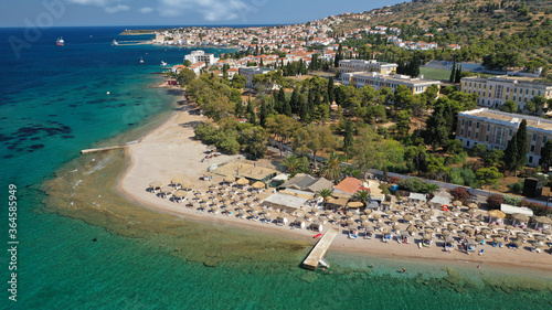 Aerial drone photo of organised with sun beds emerald beach of Kaikia in Ligoneri area near old town of Spetses island, Saronic gulf, Greece © aerial-drone