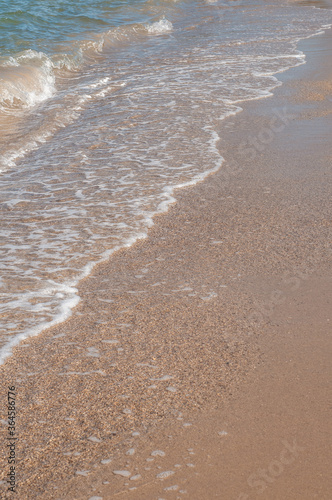 Transparent sea waves on the warm sandy seashore. Sea vacation and travel.