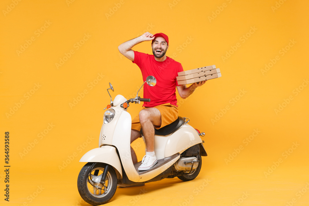 Delivery man in red cap t-shirt uniform driving moped motorbike scooter hold pizza in cardboard flatbox isolated on yellow background studio Fun guy employee working courier Service quarantine concept Delivery man in red cap t-shirt uniform driving moped motorbike scooter hold pizza in cardboard flatbox isolated on yellow background studio Fun guy employee working courier Service quarantine concept