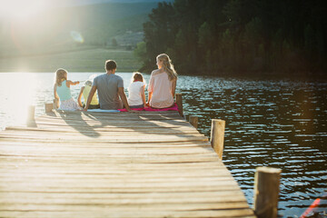 Family sitting at the edge of dock over lake