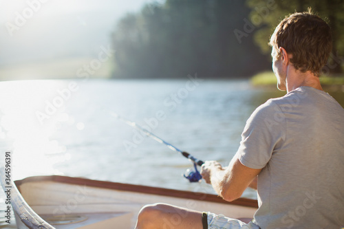 Canvas Print Man fishing in rowboat on calm lake