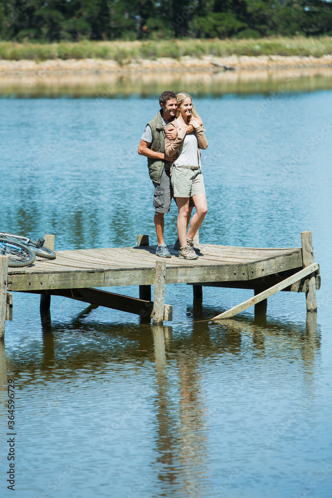 Smiling couple hugging on dock over lake