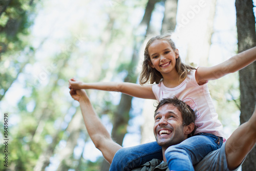 Father carrying daughter on shoulders in woods