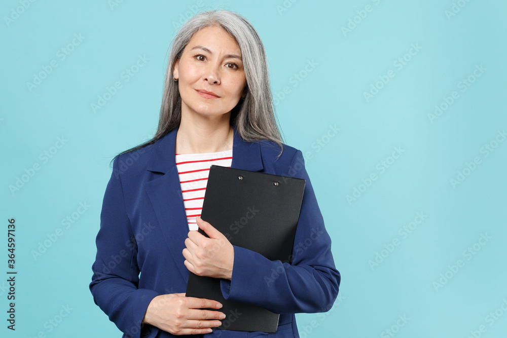 Successful gray-haired business woman in blue suit isolated on blue background studio portrait. Achievement career wealth business concept. Mock up copy space. Hold clipboard with papers document. Successful gray-haired business woman in blue suit isolated on blue background studio portrait. Achievement career wealth business concept. Mock up copy space. Hold clipboard with papers document.