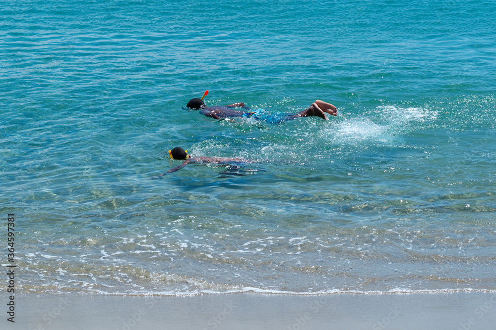 Two Black kid snorkeling in clear ocean water in Dominican Republic.