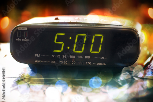 Black digital alarm radio clock.Alarm radio clock indicating time to wake up.Digital clock closeup displaying 05:00 o'clock. Digital radio clock displaying 05:00  on bokeh background