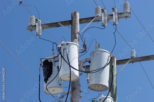 Partially scorched powerline transformers against blue sky