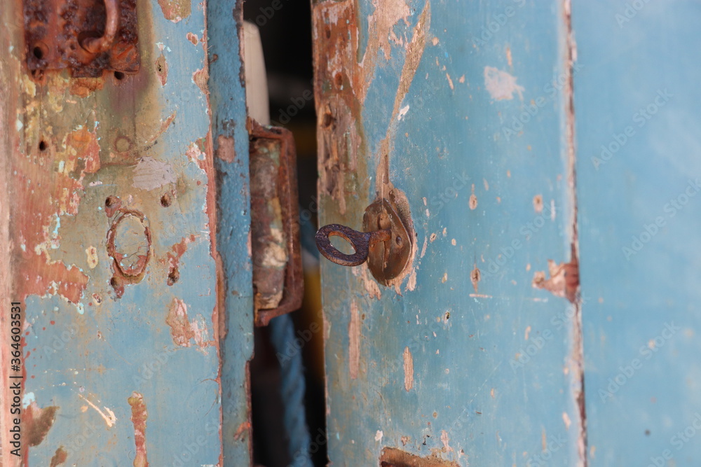 Old rusty blue door, open, close up key in lock Old rusty blue door, open, close up key in lock