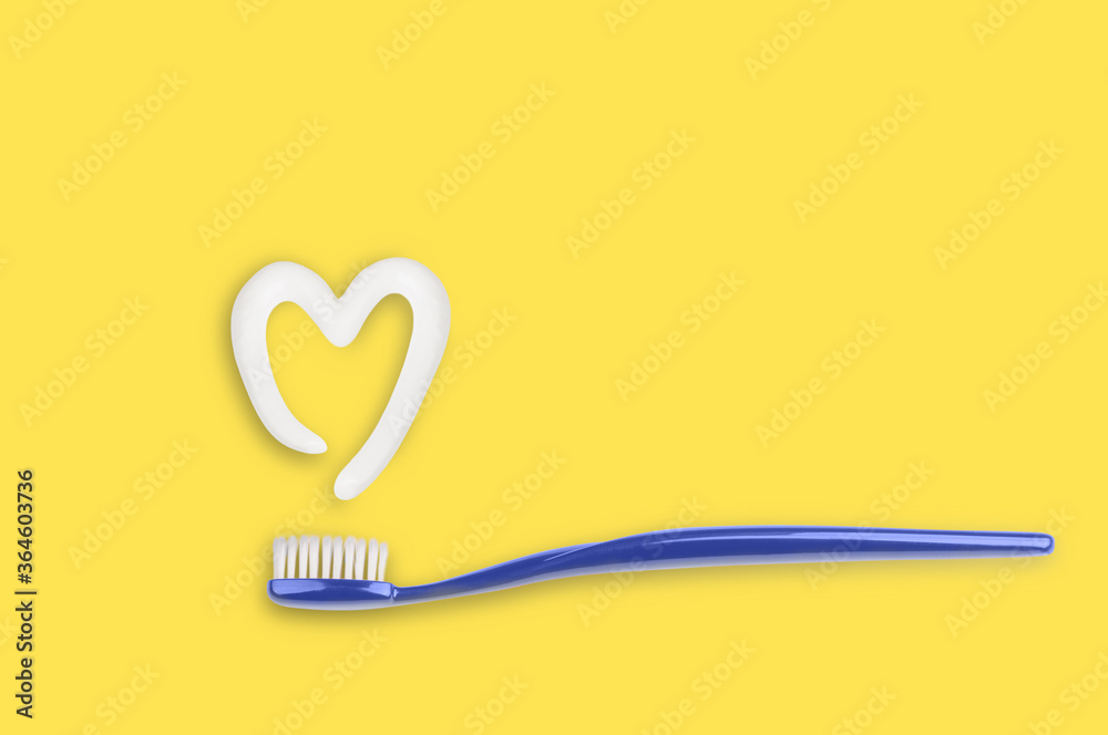 Blue toothbrush and toothpaste in shape of heart on yellow background. Blue toothbrush and toothpaste in shape of heart on yellow background.