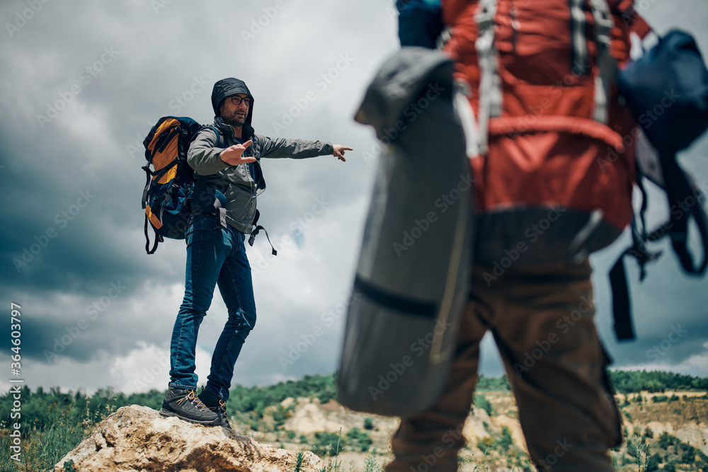 Two attractive men with backpacks hiking and searching for the good place for adjusting tent. Two attractive men with backpacks hiking and searching for the good place for adjusting tent.