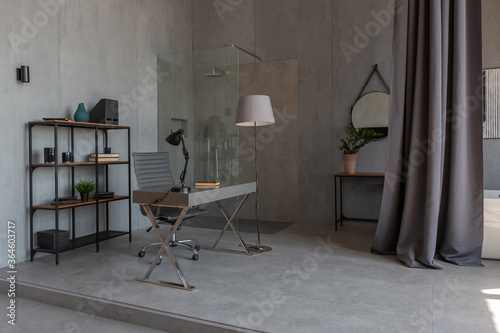 Modern minimalistic dark gray loft style studio apartment interior design. kitchen, sitting area, workplace, shower and bath. bright sun rays inside.