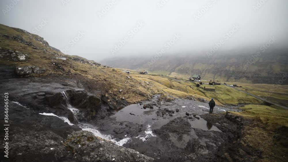 Man Standing In Stream From Waterfall Man Standing In Stream From Waterfall