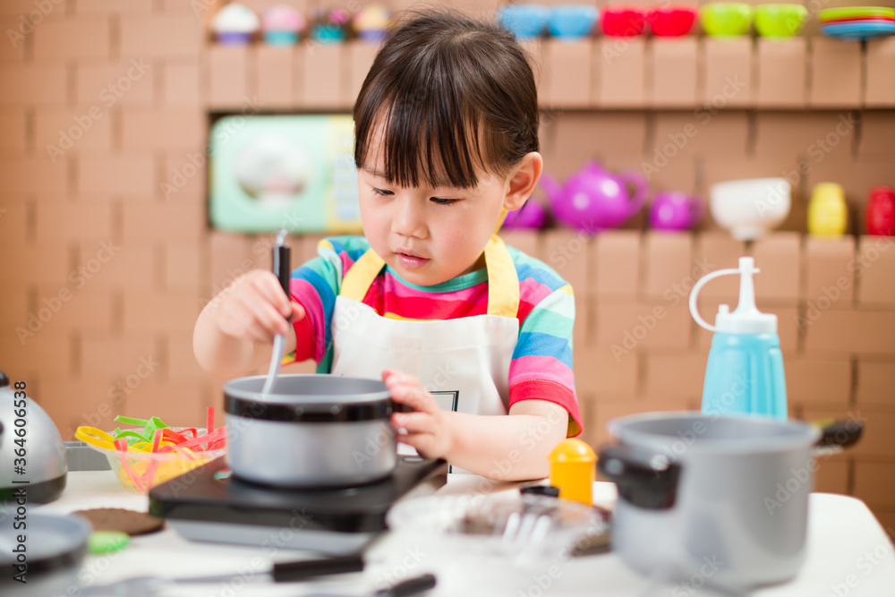toddler girl pretend play food preparing role against cardboard blocks kitchen background toddler girl pretend play food preparing role against cardboard blocks kitchen background