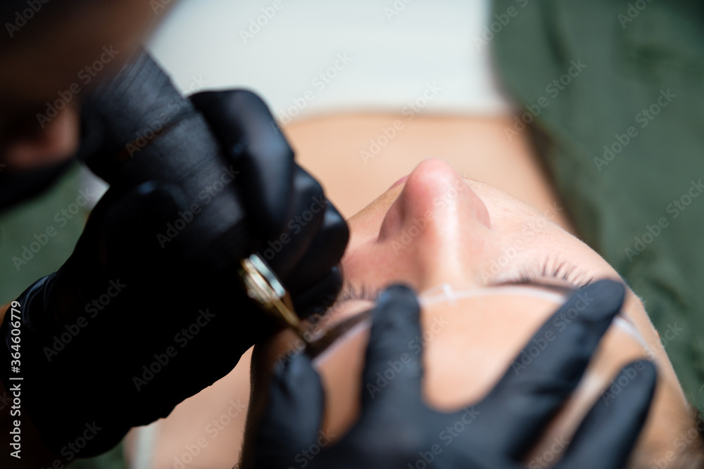 The girl artist paints an eyebrow tattoo. The process of tattooing. Permanent makeup	
