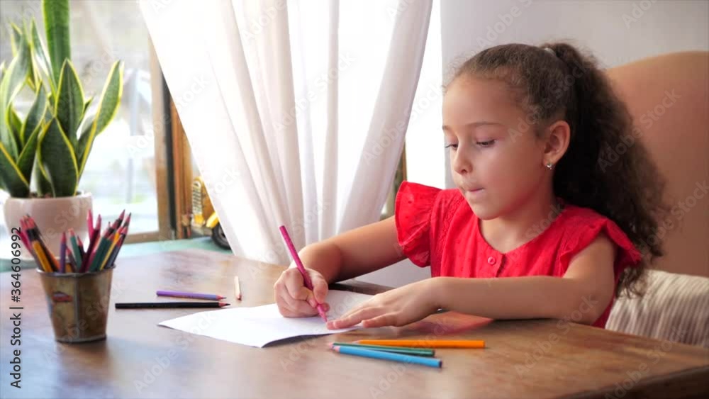 Cute small little girl or child school child of 7-8 years old at home relaxing artist playing alone drawing coloring picture with at home relaxing sits and paints on paper use colour pencils. Cute small little girl or child school child of 7-8 years old at home relaxing artist playing alone drawing coloring picture with at home relaxing sits and paints on paper use colour pencils.