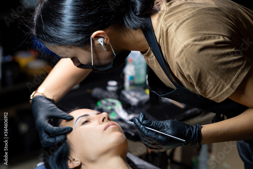 The girl artist paints an eyebrow tattoo. The process of tattooing. Permanent makeup 