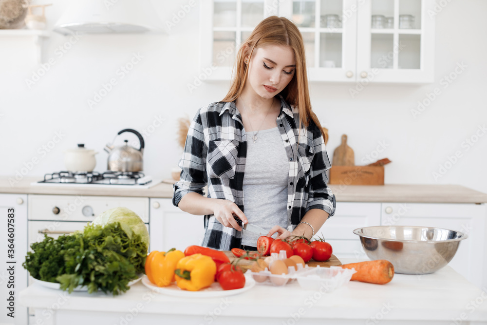 Young woman cooking at home at kitchen with tablet in ear plugs