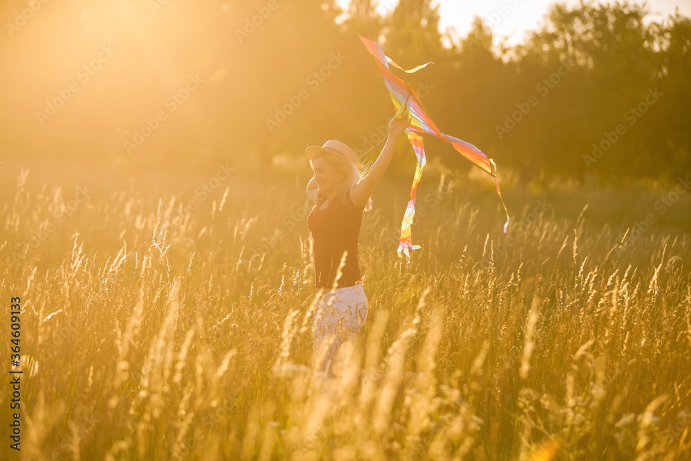 Portrait of a young and carefree woman launching kite on the greenfield. Concept of active lifestyle in nature - obrazy, fototapety, plakaty 