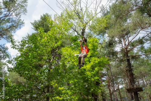woman facial mask jumping on a zip line in a pine forest
