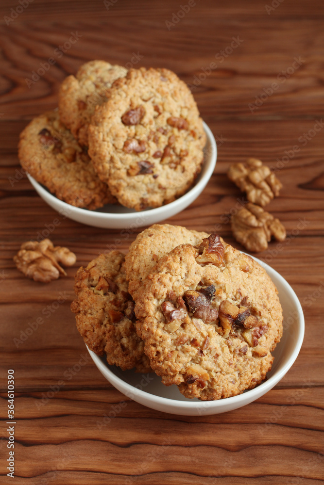 Oatmeal cookies with walnuts and raisins on small saucers standing on a wooden table. Closeup Oatmeal cookies with walnuts and raisins on small saucers standing on a wooden table. Closeup