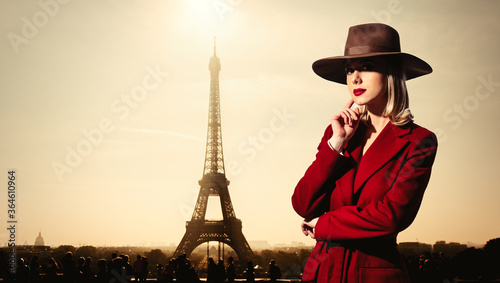girl in red coat and vintage hat with Parisian Eiffel tower on background.