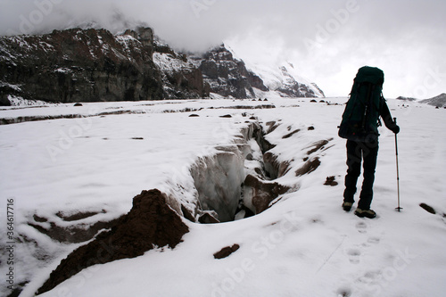 Mountaineer climbing Mount Kazbek and deep glacier crack in Georgia. Mount Kazbek is highest mountain in Georgia. photo