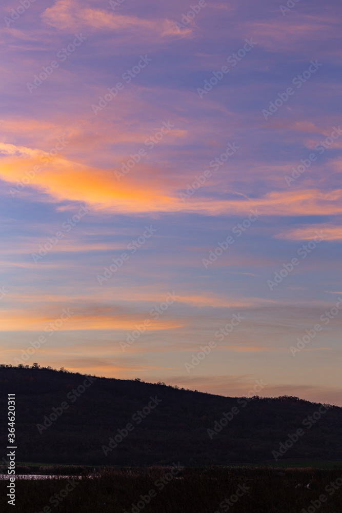 Purple-magenta clouds. Landscape with bloody  dawn. The terrain in southern Europe.  Panorama. Mirror lake with a reflection of nature. Morning silence. Water surface.