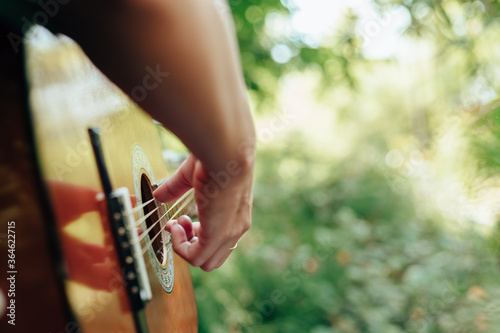 woman's hands playing acoustic guitar have fun outdoor, close up.