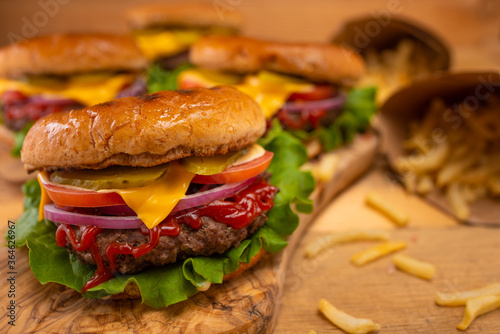 Hamburger or burger with french fries on a wooden background, tasty and unhealthy food, fast food
