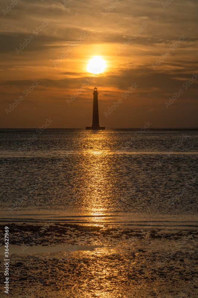 The historic Morris Island Lighthouse is topped by the morning sun rising above the Atlantic Ocean near Charleston, South Carolina. Photographed the beach on Folly Island.